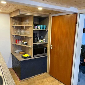 A compact kitchen with wooden shelves, a microwave, and a door leading to another room. - Arode Ferienhaus Harzensfreund, in the Center of Mountainresort St. Andreasberg (Sankt Andreasberg)