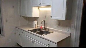 Una cocina con dos fregaderos, armarios blancos y una encimera.