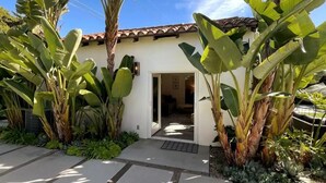 A house with a tiled roof, a door, and large banana plants in the garden. - Private Guest House Central Location-Dog Friendly (Santa Barbara)
