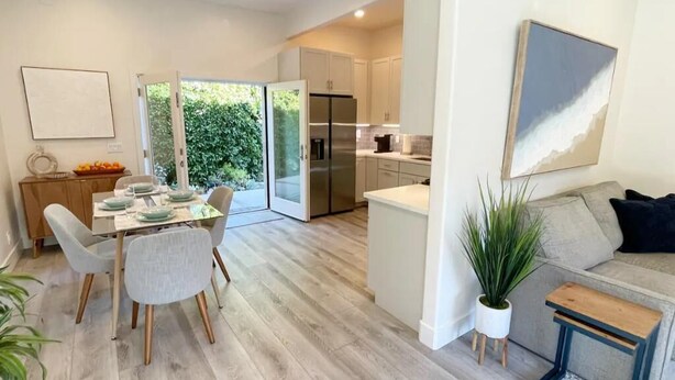 A modern kitchen with a built-in refrigerator, a dining area with a table and chairs, and a living area with a sofa and a plant. - Private Guest House Central Location-Dog Friendly (Santa Barbara)
