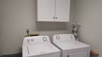 A laundry room with two front-loading washing machines and a white cabinet above.