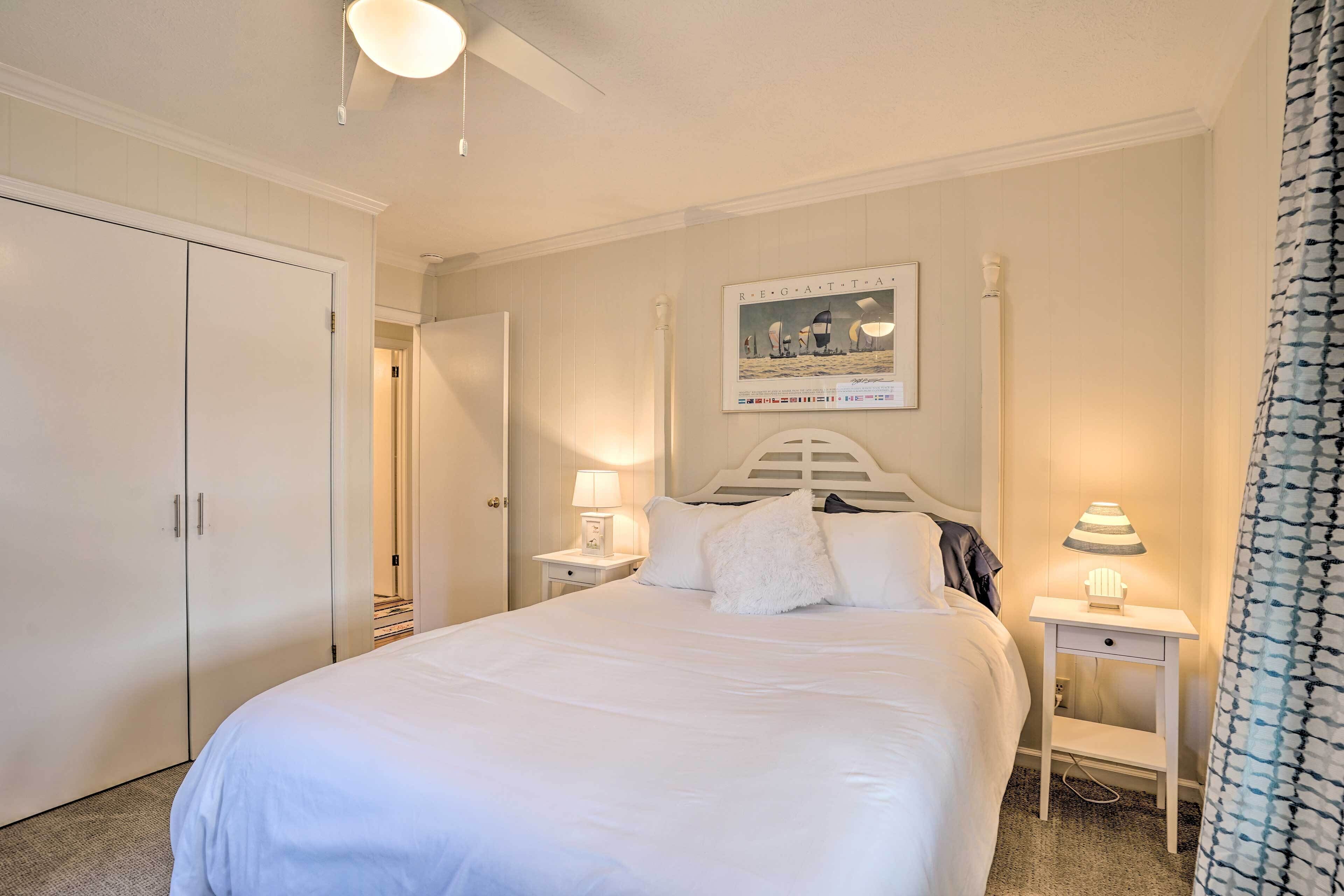 A neatly arranged bedroom with a large bed, a wardrobe, and a nightstand with a lamp.