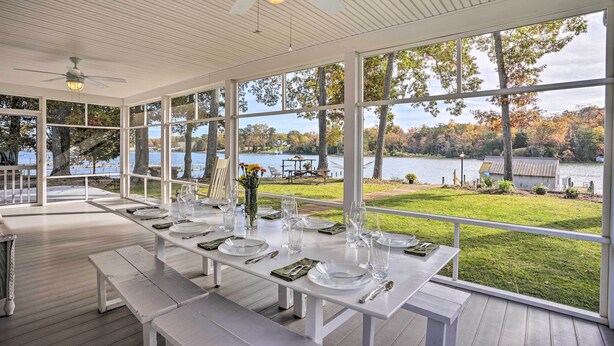 A dining area with a view of a lake and trees, featuring white tables and benches, ceiling fans, and large windows. - RivahMojo on Mill Creek-just off RappahannockRiver (Topping)