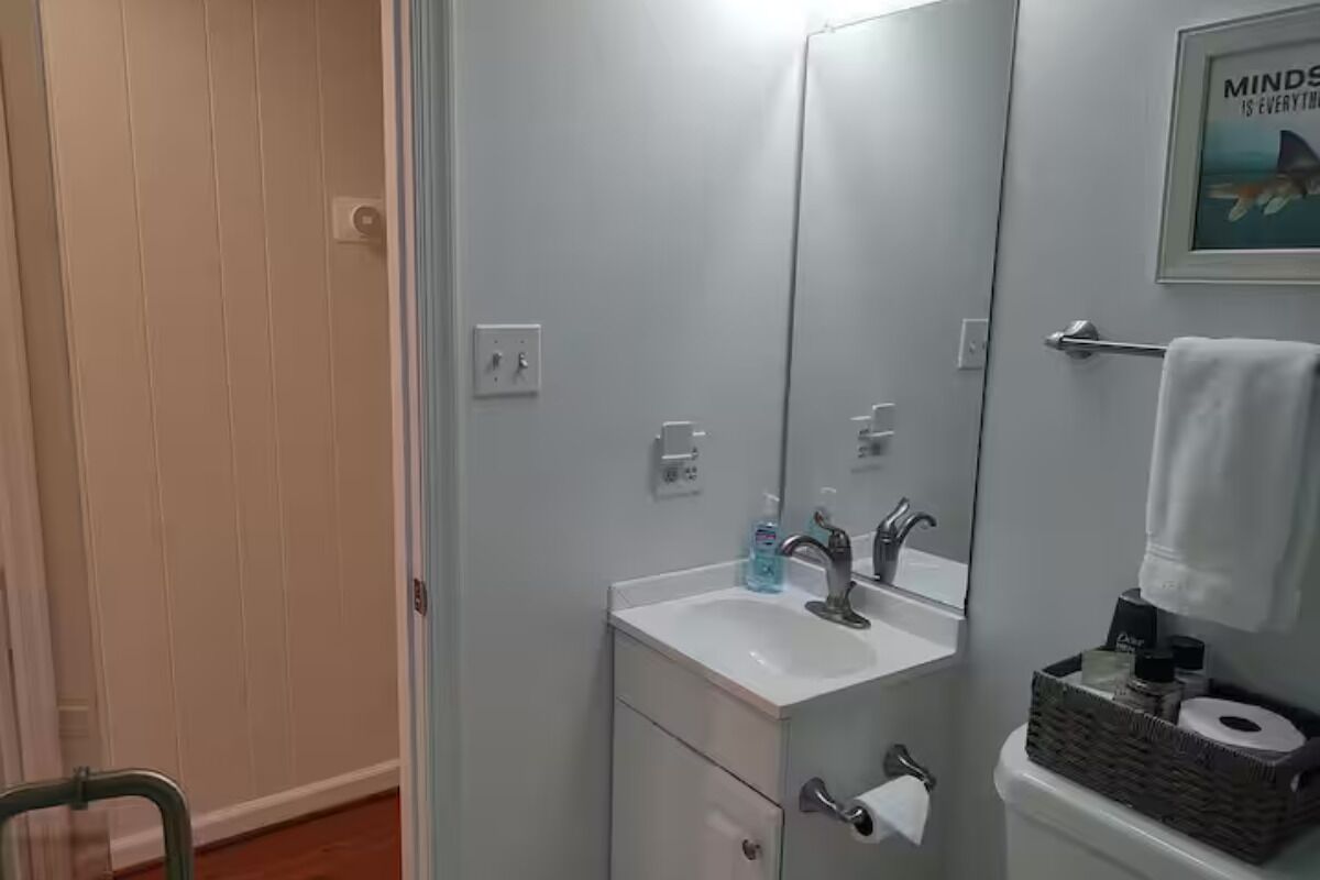 Une salle de bain avec un lavabo blanc, un miroir et un porte-serviettes.