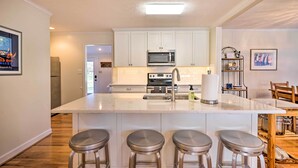 A modern kitchen with white cabinets, a central island with stools, stainless steel appliances, and a bright overhead light. - RivahMojo on Mill Creek-just off RappahannockRiver (Topping)