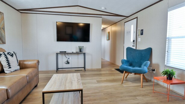 A modern living room with a leather sofa, a blue armchair, a wooden coffee table, and a flat-screen TV mounted on the wall. - Red Sands Habitation 3 - Close to Downtown (Moab)