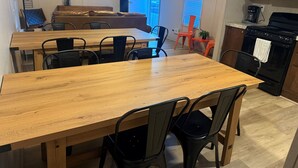 A kitchen with a wooden dining table, black chairs, a stove, and a TV mounted on the wall. - Red Sands Retreat D - 3 Bedroom 2 Bath (Moab)