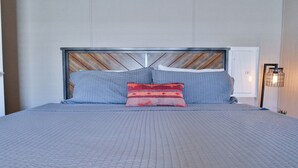A bed with a wooden headboard, grey bedding, and a red patterned pillow. - Red Sands Retreat D - 3 Bedroom 2 Bath (Moab)