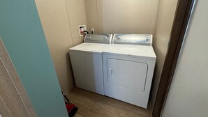 A compact laundry room with two washing machines, a power outlet, and a broom. - Red Sands Retreat D - 3 Bedroom 2 Bath (Moab)
