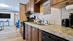 Une cuisine moderne avec des meubles en bois, un plan de travail en granit et un lave-vaisselle encastré.