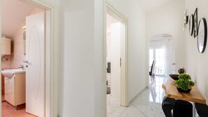 A modern interior with a kitchen, dining area, and a hallway leading to another room.