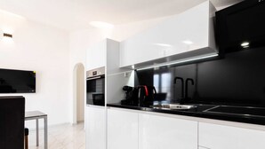 A modern kitchen with white cabinets, a black countertop, and stainless steel appliances.