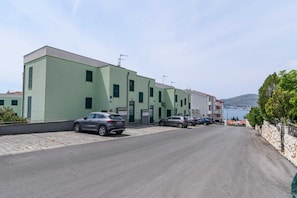 Un edificio de techo plano, con varias ventanas y un estacionamiento lleno de coches.