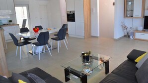 Un salon moderne avec une table basse en verre, un canapé et un coin repas comprenant des chaises et une table.