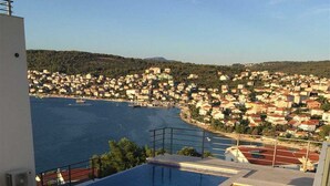 Une piscine sur le toit, dotée de chaises longues, offrant une vue sur une ville côtière.