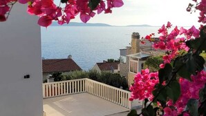 A coastal view with bougainvillea flowers, a white building, and a clear sky.