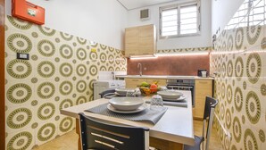 Une cuisine compacte avec un coin repas, agrémentée de carreaux décoratifs, d’un évier et d’appareils électroménagers de base.