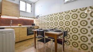 Une cuisine compacte avec un coin repas, dotée d’un crédence décorée, d’un four encastré et d’une petite fenêtre.
