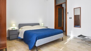 Une chambre à coucher comprenant un lit, des tables de chevet, une armoire et un miroir.