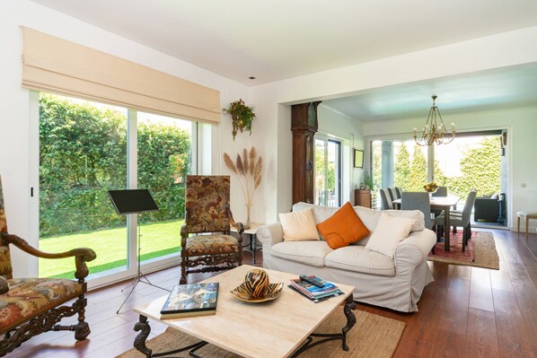 A spacious living room with a large window, a sofa, a coffee table, and a dining area.