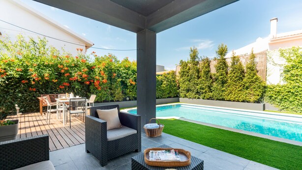 Un patio couvert aménagé avec du mobilier d’extérieur, une piscine et une pelouse bien entretenue.