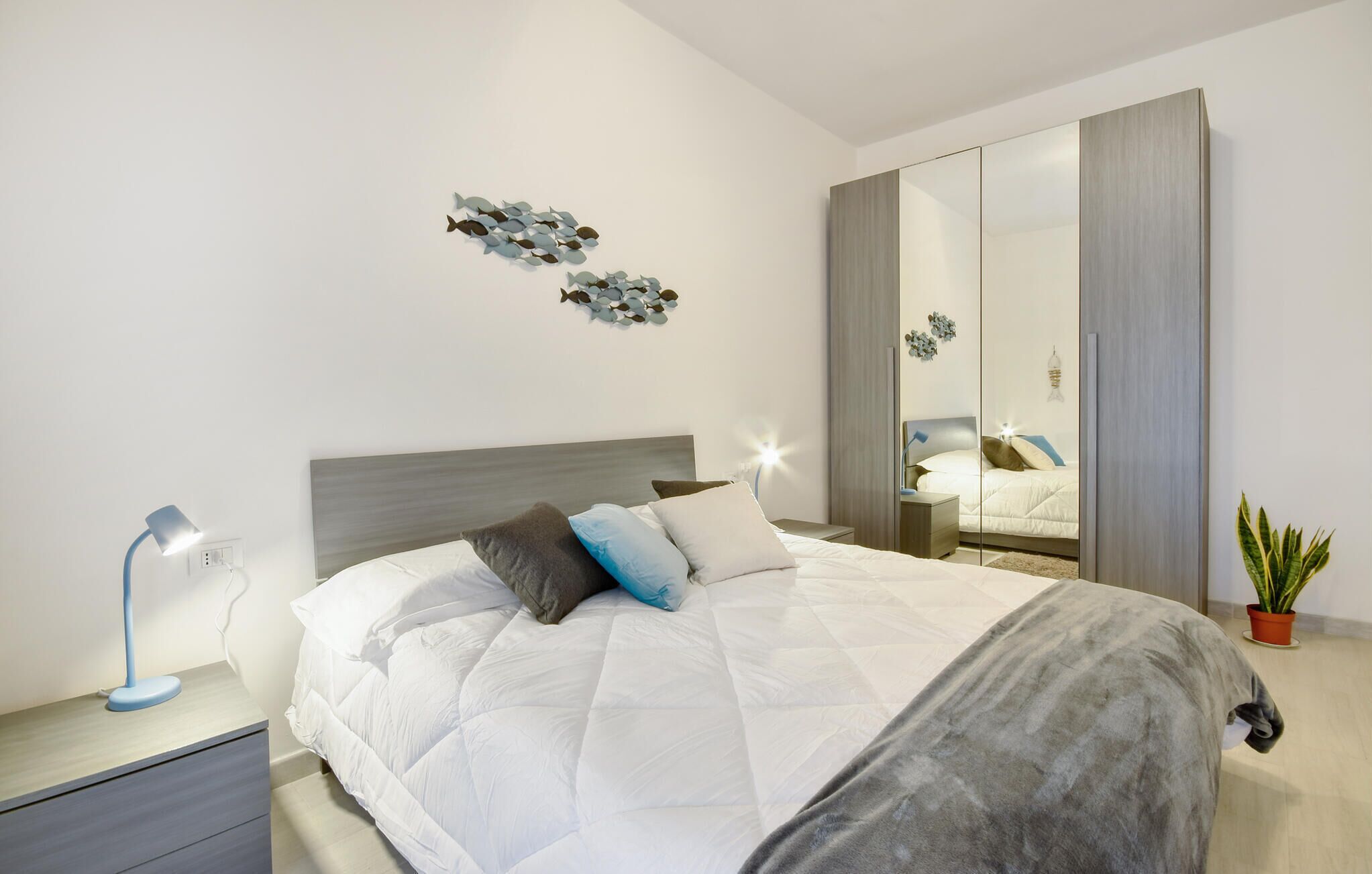 Ein modernes Schlafzimmer mit einem großen Bett, Nachttischen, einem Spiegel und Wanddekoration.