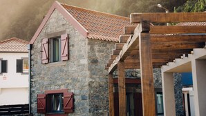 Un edificio de piedra con techo de tejas y pérgola de madera.