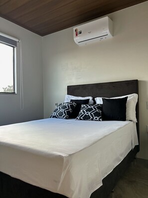 Relax in a serene bedroom with a large bed, air conditioning, and minimalist design.