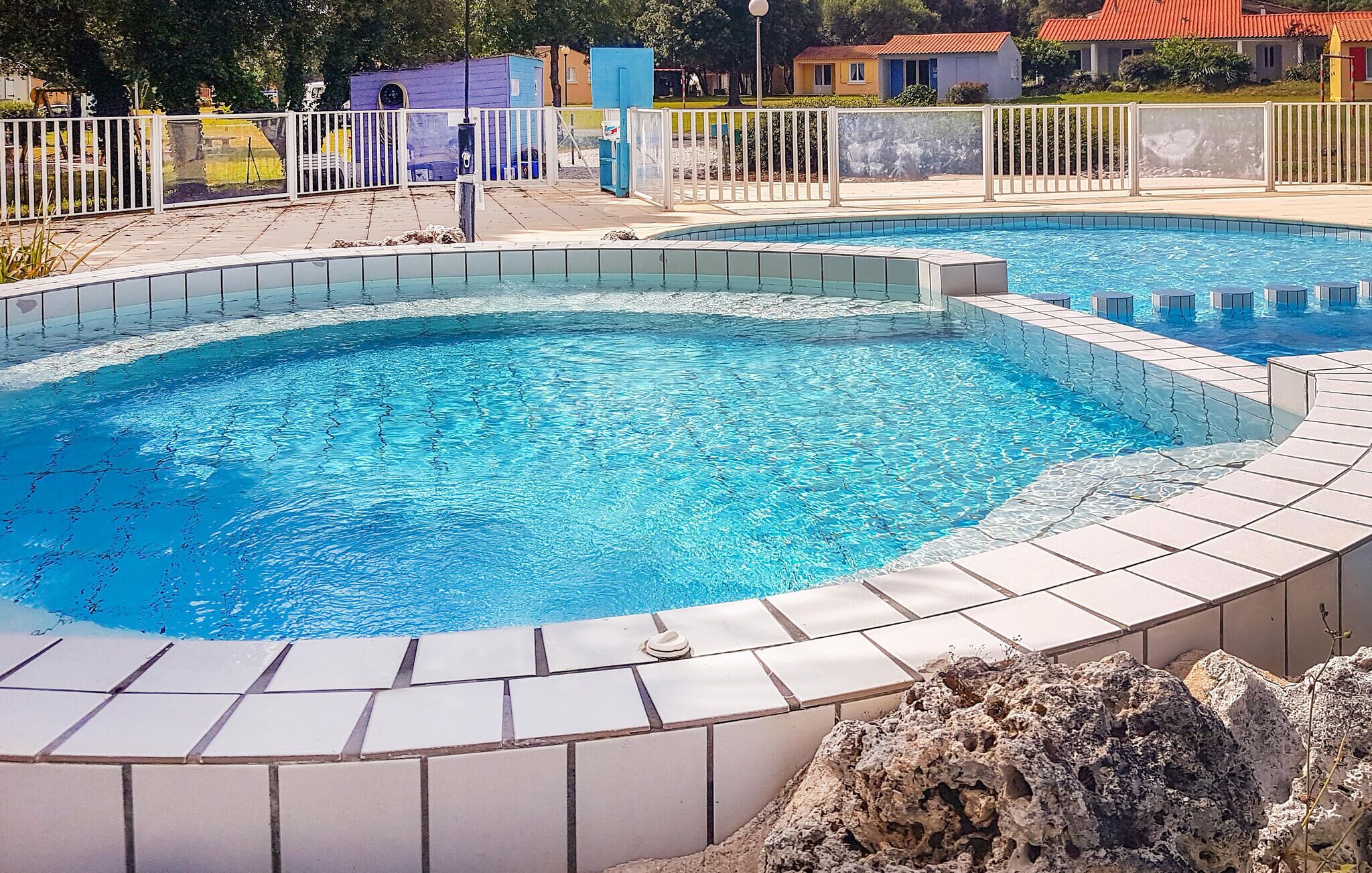 A swimming pool with a tiled edge and a surrounding fence.