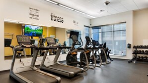 A fitness center with treadmills, a mirrored wall, and a motivational quote.