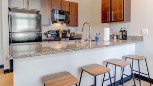 A modern kitchen with stainless steel appliances, wooden cabinets, and a granite countertop.
