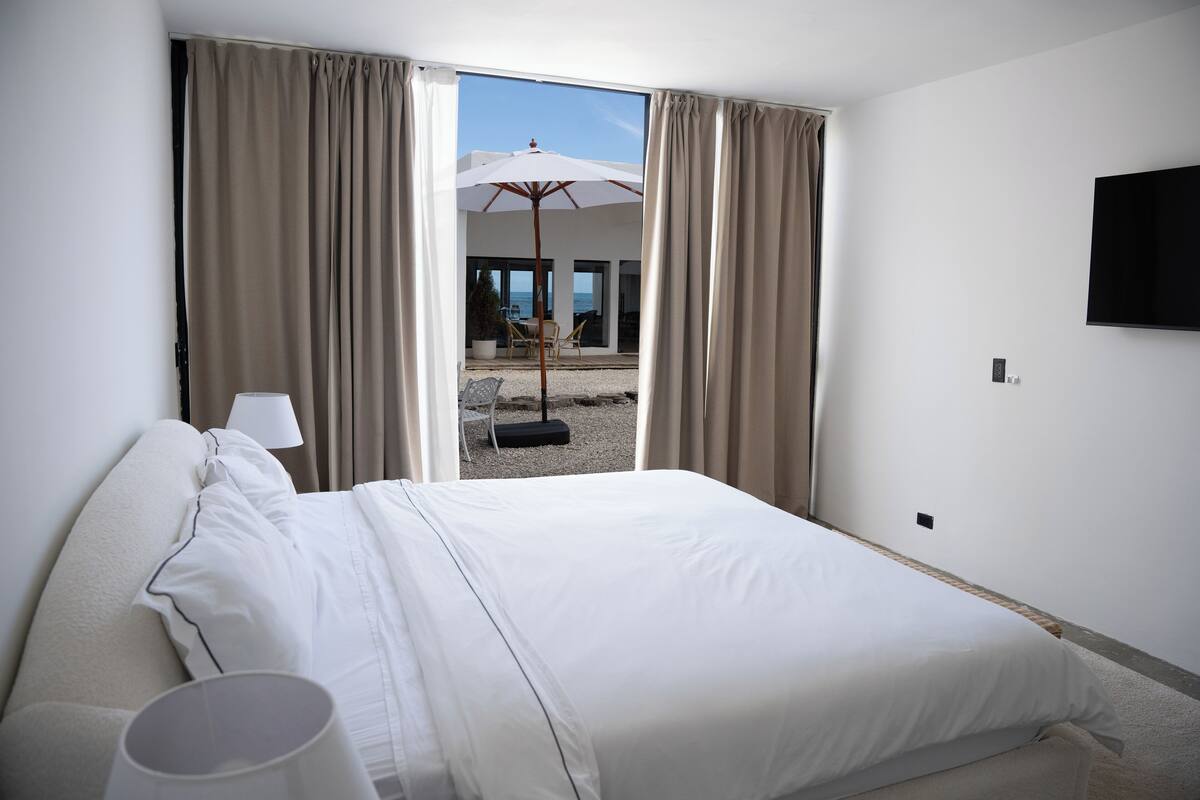 Habitación de hotel con cama, cortinas, televisión y vistas al exterior.