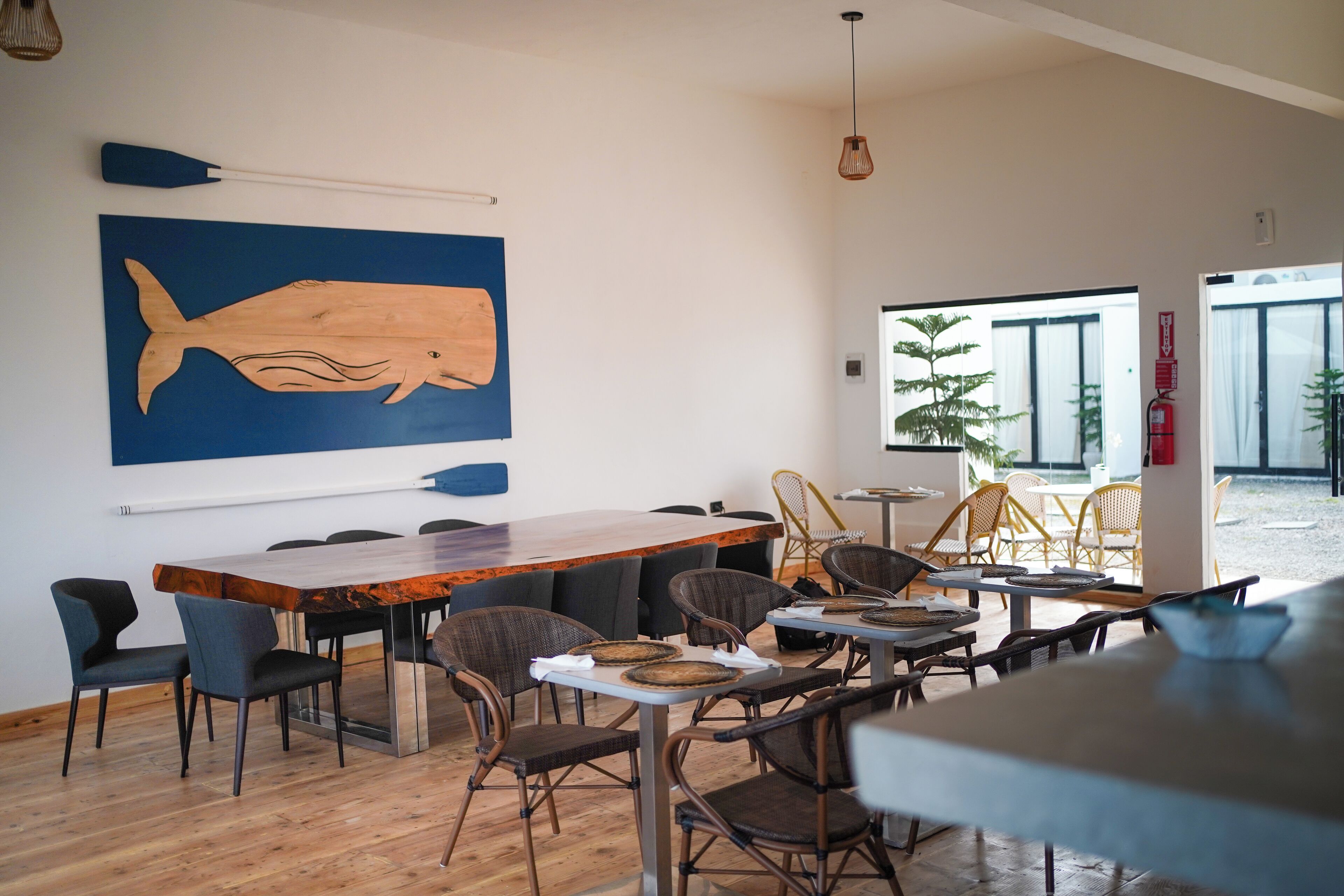 A modern dining area with a large wooden table, comfortable chairs, and a large whale mural on the wall.