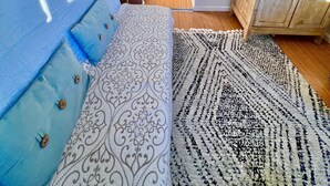 A compact living space with a sofa, a patterned rug, a wooden cabinet, and a kitchenette in the background.