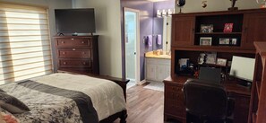 Relax in a spacious bedroom with a large bed, flat-screen TV, and desk for work.