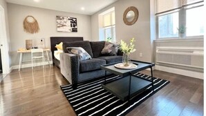 A modern living room with a grey sofa, a black coffee table, and a striped rug.