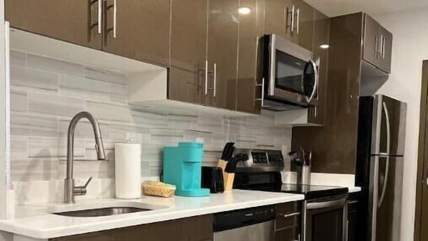 A modern kitchen with stainless steel appliances, a microwave, and a dishwasher. - 306 Deluxe King suite in the center city (Philadelphia)
