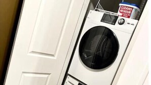 A laundry room with two stacked front-loading washing machines and a container of detergent on top. - 306 Deluxe King suite in the center city (Philadelphia)