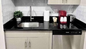 A modern kitchen with stainless steel appliances, beige cabinetry, and a black countertop. - 402 Stylish luxe Apt at center city self check-in (Philadelphia)