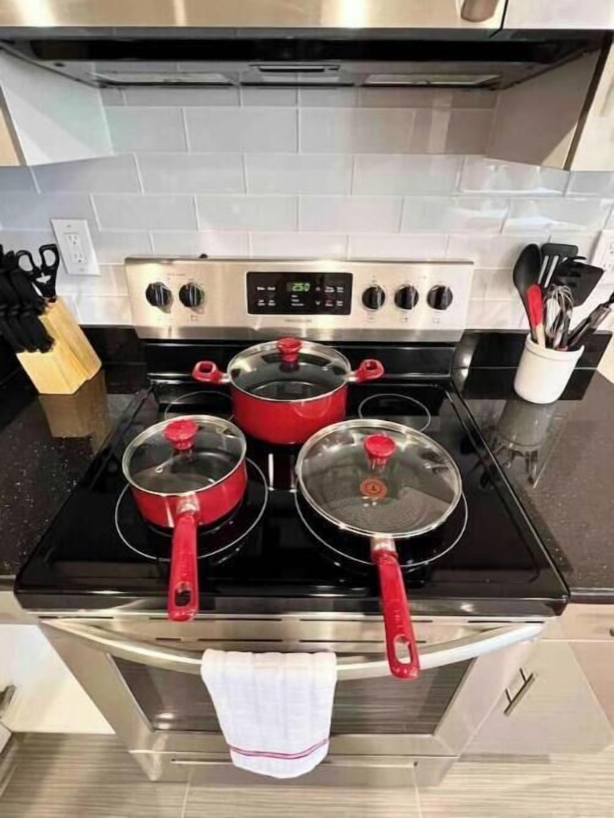 A kitchen with a stove, pots, and a utensil holder.