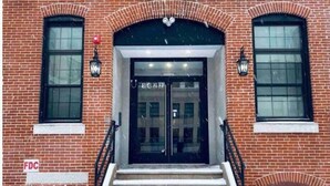 A brick building with a double door entrance, two windows on either side, and a staircase leading up to the door. - 402 Stylish luxe Apt at center city self check-in (Philadelphia)