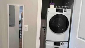 A laundry room with two stacked front-loading washing machines and a mirror on the left wall. - 405 Spacious and superior 1BDR APT in center city (Philadelphia)