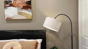 A bedroom with a bed, a floor lamp, a painting, and a potted plant. - 405 Spacious and superior 1BDR APT in center city (Philadelphia)