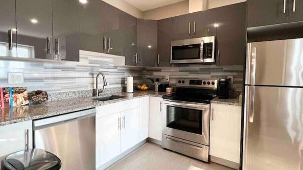 A modern kitchen with stainless steel appliances, white cabinetry, and a granite countertop. - 504 Luexy 1BDR apt in center city (Philadelphia)
