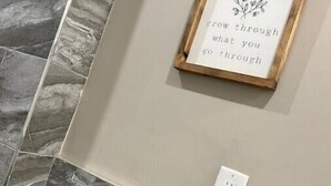 A bathroom with a tiled floor, a framed inspirational quote on the wall, a power outlet, and a potted plant. - 508 Urban Lifestyle king bed APT in Center city (Philadelphia)