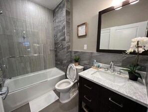 A modern bathroom with a bathtub, toilet, and sink. - 508 Urban Lifestyle king bed APT in Center city (Philadelphia)