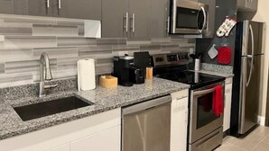 A modern kitchen with grey cabinets, stainless steel appliances, and a granite countertop. - 508 Urban Lifestyle king bed APT in Center city (Philadelphia)