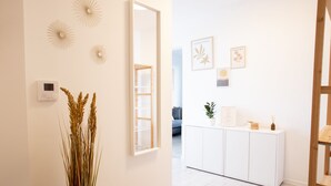 A modern interior with a white console table, decorative wall art, and a potted plant. - Lomená Apartment
 (Košický kraj)