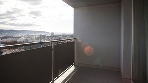 A balcony with a city view, a tiled floor, and a metal railing. - Lomená Apartment
 (Košický kraj)