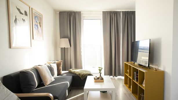 A modern living room with a sofa, coffee table, and TV stand. - Lomená Apartment
 (Košický kraj)